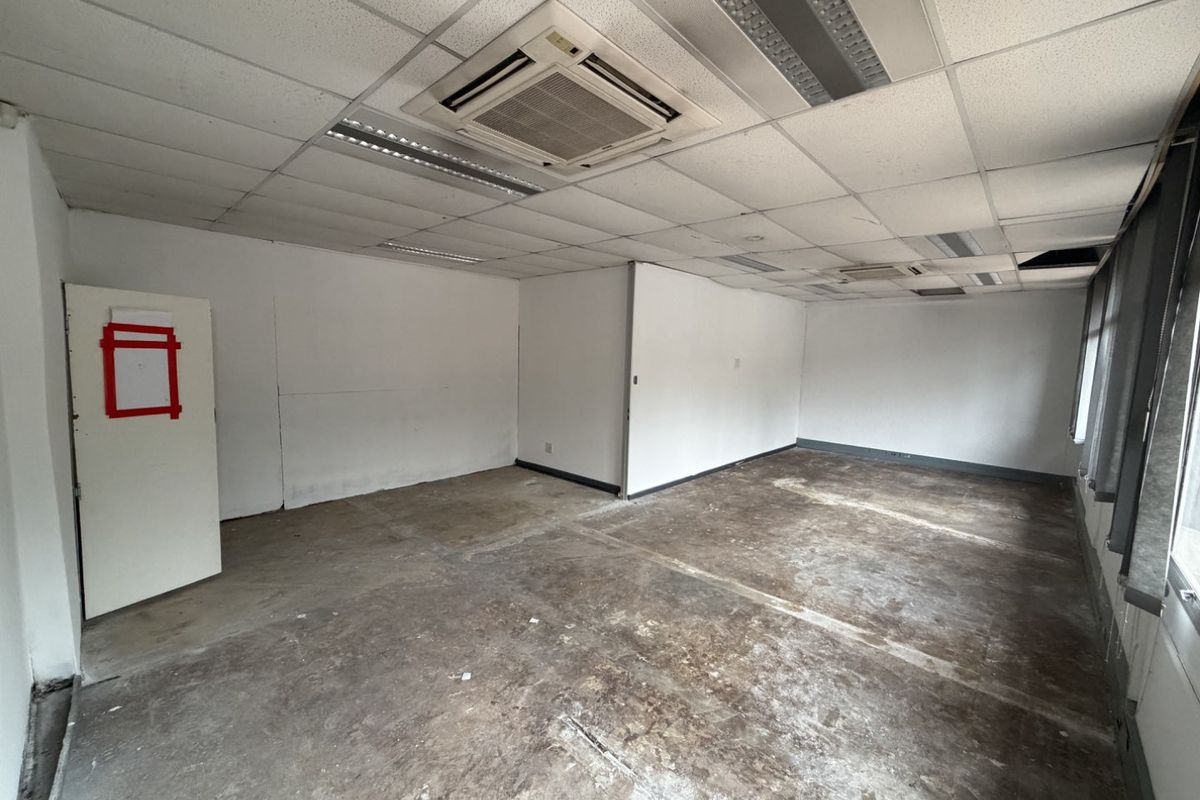 An empty industrial office space featuring a suspended ceiling with integrated air conditioning and lighting, requiring flooring and wall finishing.