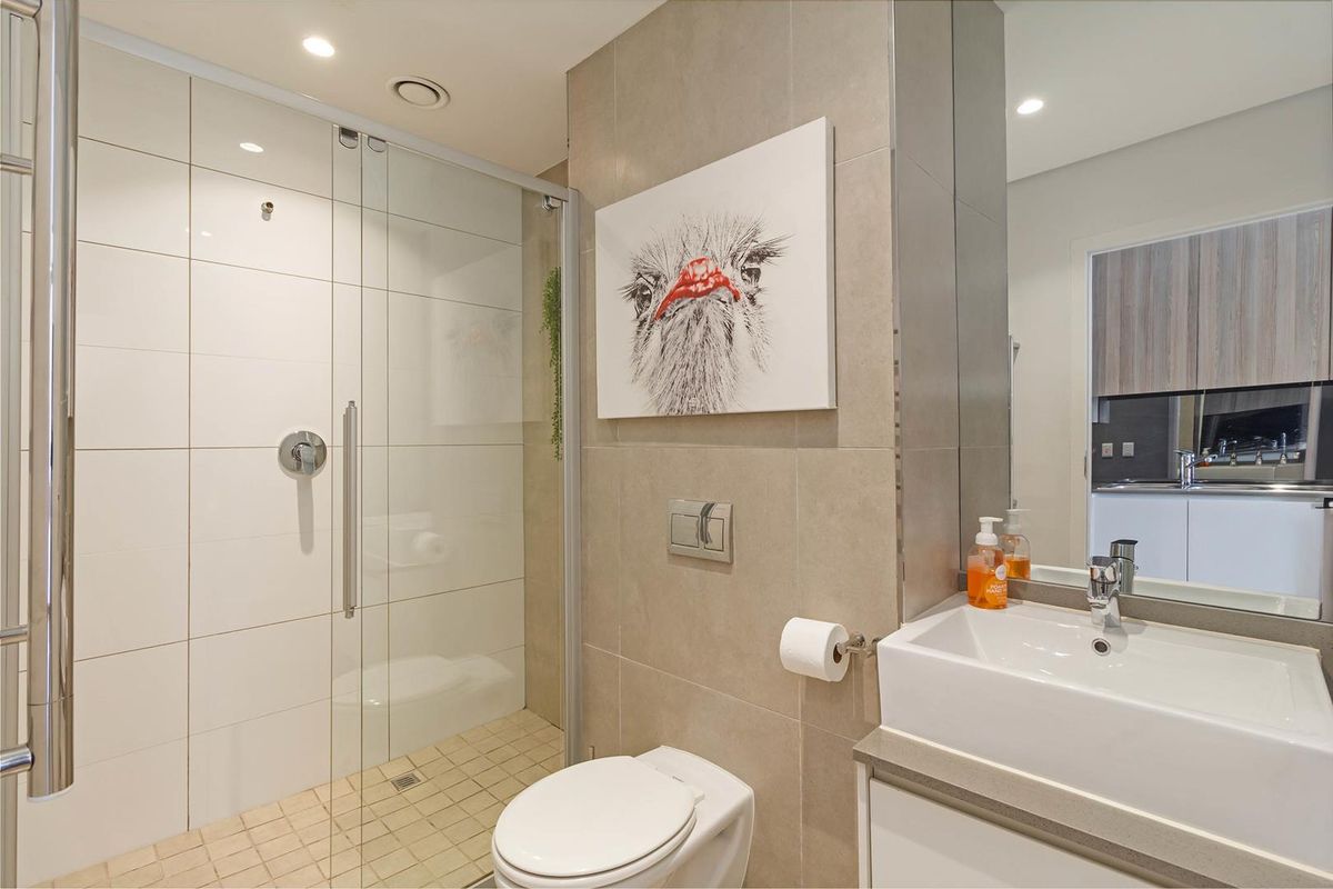 Modern bathroom featuring a walk-in shower with glass screen, wall-mounted toilet, and a sleek vanity basin with contemporary fixtures.