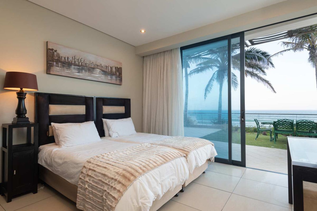 A well-maintained bedroom featuring large sliding glass doors that open onto a patio with ocean views and tiled flooring throughout.