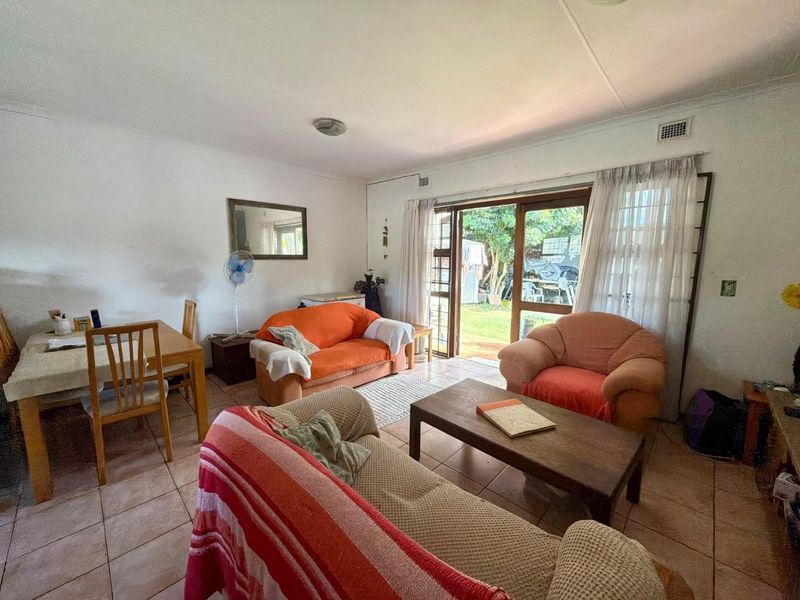 Open-plan living and dining area featuring tiled flooring and a sliding glass door providing direct access to the rear garden.