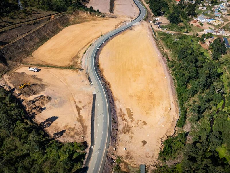 Aerial view of a cleared industrial development site featuring a paved access road and surrounding natural landscape.