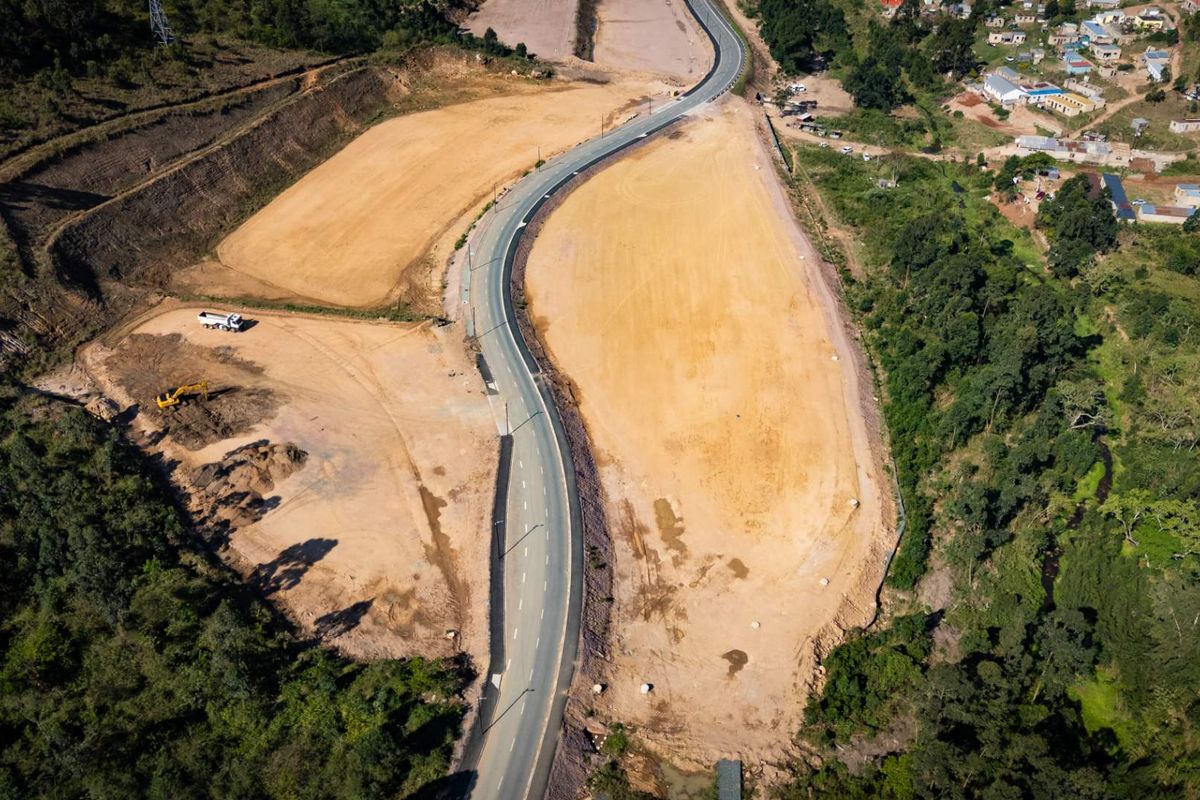 Aerial view of a cleared industrial development site featuring a paved access road and surrounding natural landscape.