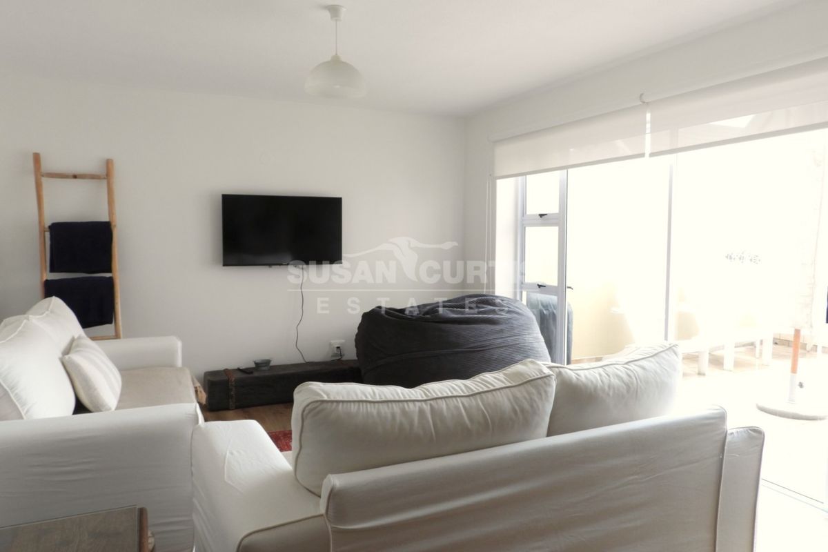 A bright living room featuring a sliding glass door with a roller blind, providing natural light and access to the outdoor area.