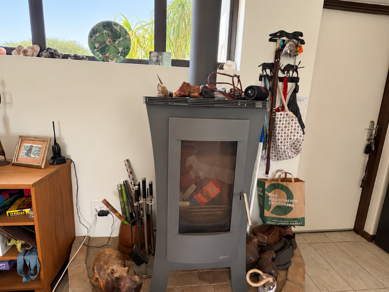 A living room area featuring a modern freestanding fireplace set on a raised circular brick hearth with tiled flooring and a horizontal window.