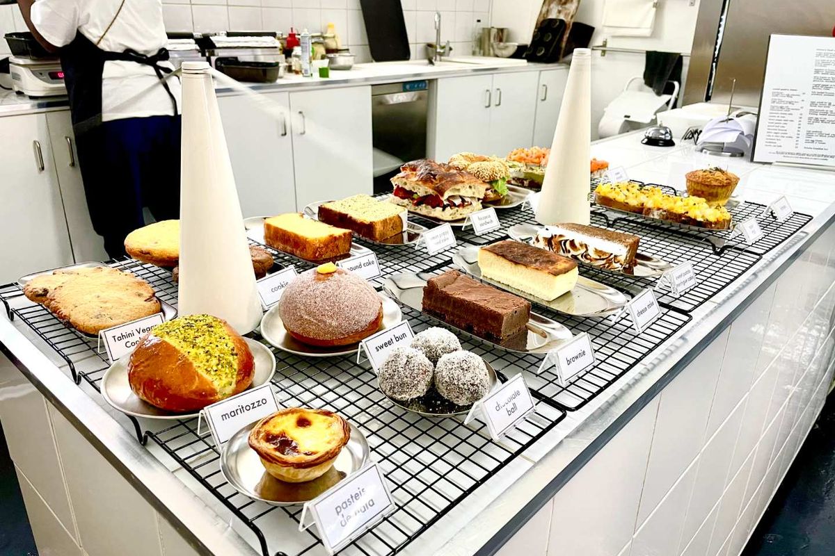 A commercial-style kitchen workspace featuring white cabinetry, tiled splashbacks, and a large central preparation counter.
