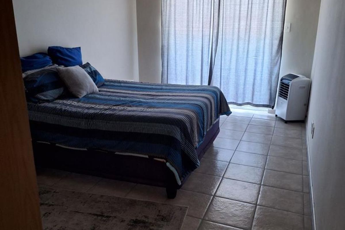 A bedroom featuring tiled flooring and a sliding glass door with curtain track, providing access to an outdoor area.