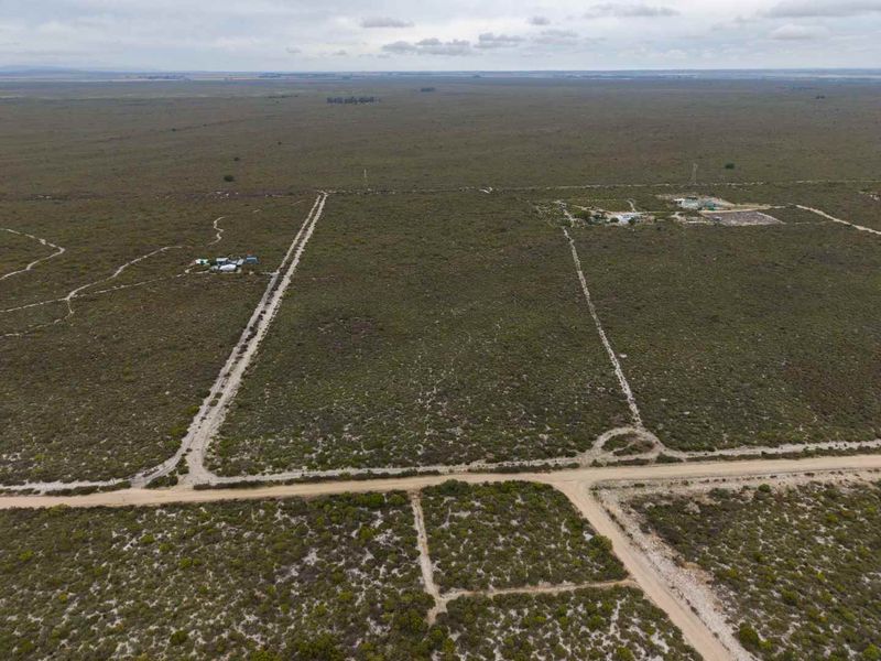 Aerial view of expansive agricultural land featuring dirt access roads and cleared plots, suitable for development or farming.