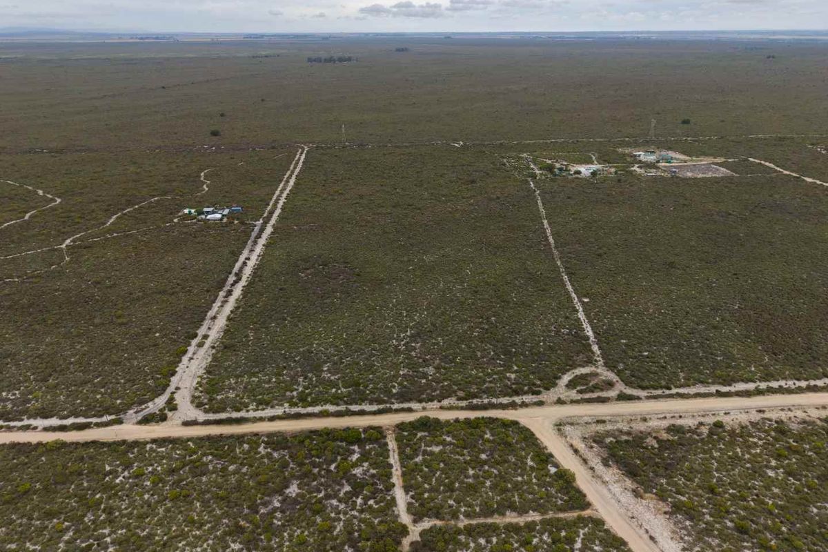Aerial view of expansive agricultural land featuring dirt access roads and cleared plots, suitable for development or farming.
