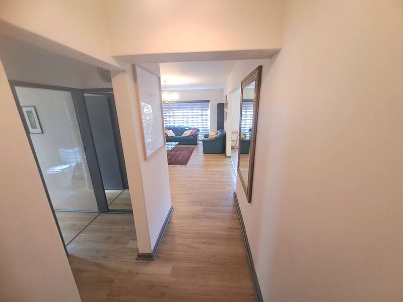 A bright hallway with laminate flooring providing access to the living area and adjacent rooms, featuring neutral walls and clean finishes.