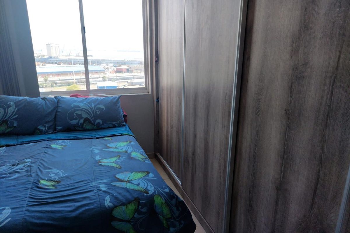 A bedroom featuring a large built-in wardrobe with wood-grain finish sliding doors and a window offering an industrial city view.