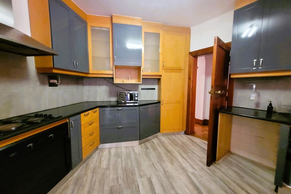 A functional kitchen featuring two-tone cabinetry, dark stone countertops, integrated oven, and hob with an extractor fan.