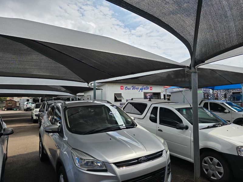 Exterior view of a commercial vehicle dealership lot featuring extensive shade cloth canopy structures and paved parking areas.