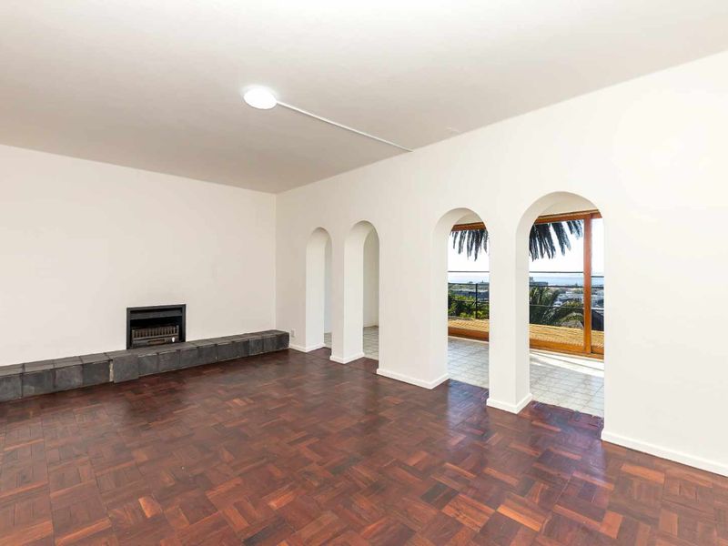 Spacious living room featuring classic parquet flooring, a built-in fireplace, and elegant arched doorways leading to an outdoor balcony with scenic views.