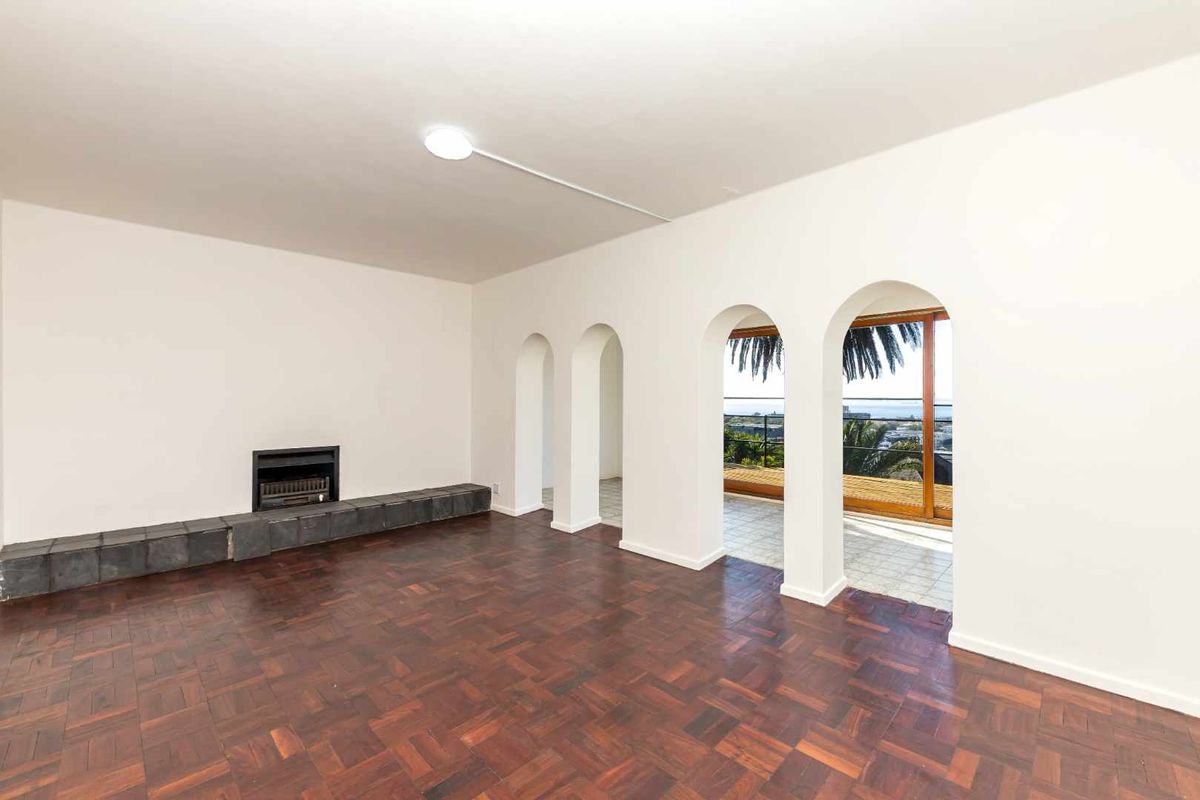 Spacious living room featuring classic parquet flooring, a built-in fireplace, and elegant arched doorways leading to an outdoor balcony with scenic views.