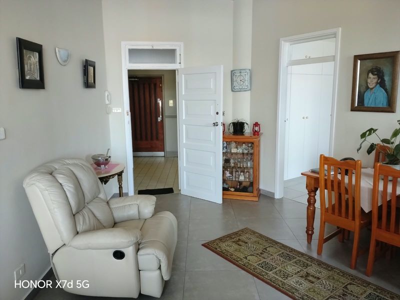 A living area featuring tiled flooring and access to the entrance hall and adjacent rooms, with neutral wall finishes.