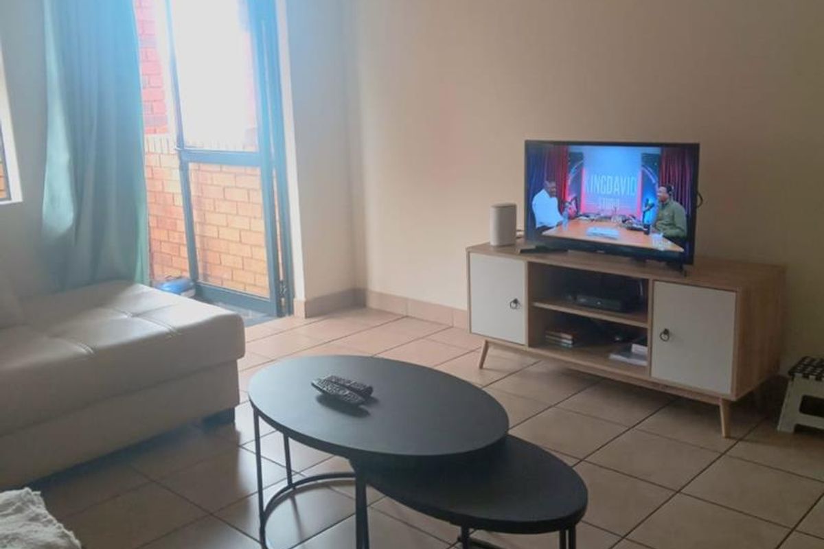 A living room featuring tiled flooring and a glass sliding door providing access to the exterior.