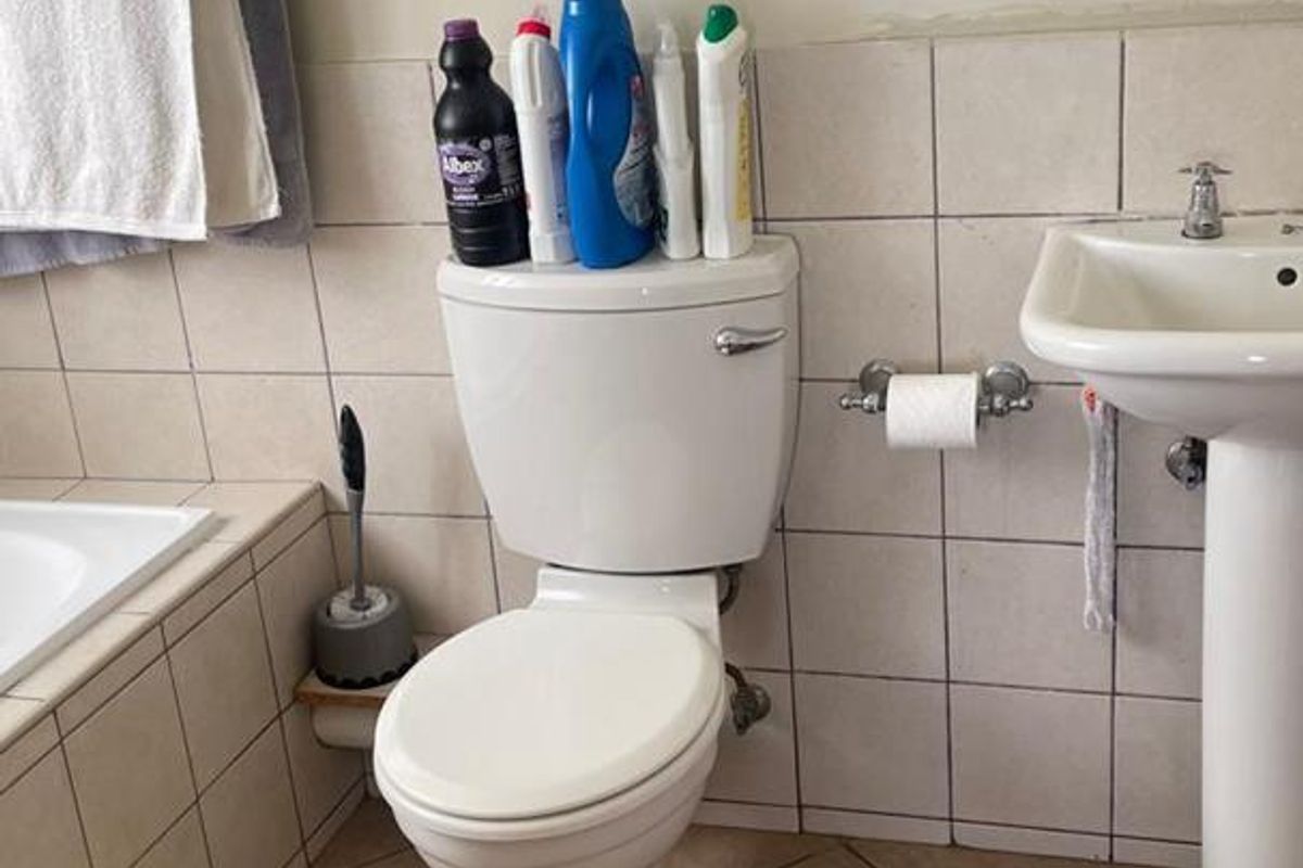 A functional bathroom featuring a pedestal basin, toilet, and built-in bathtub with ceramic tiling throughout. The space requires minor cosmetic updates and finishing.