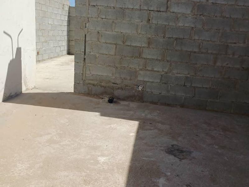 An unfinished outdoor rear area featuring exposed concrete block walls and a raw concrete slab floor, awaiting final finishes and landscaping.