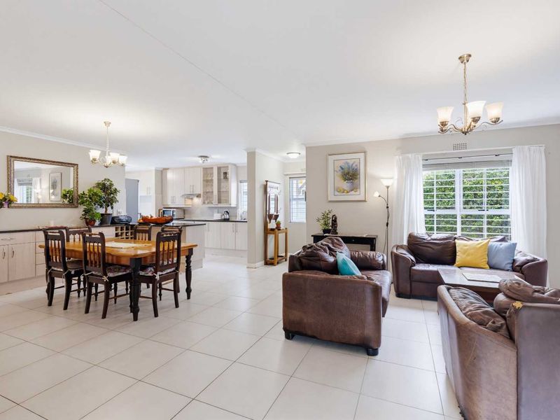 Spacious open-plan living and dining area featuring tiled floors, integrated kitchen cabinetry, and ample natural light through large windows.