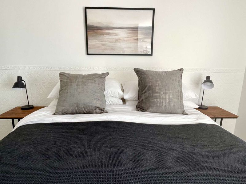 A well-presented bedroom featuring decorative textured wall paneling behind the bed area.