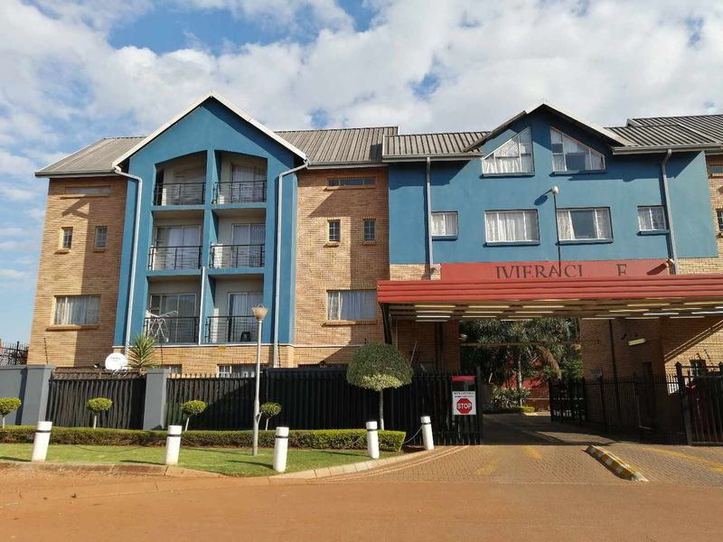 Front exterior view of the Riviera apartment complex featuring brick and blue facade, balconies, and a secure gated entrance.