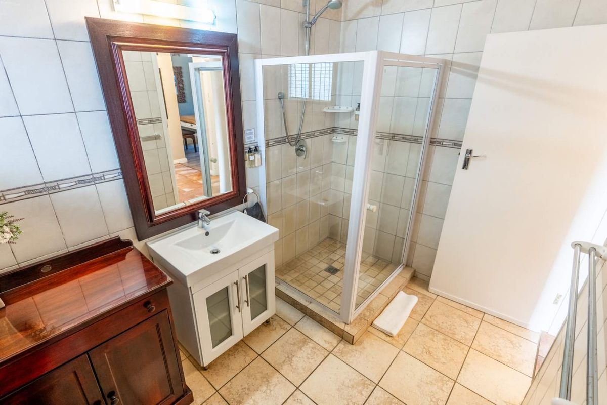 A functional bathroom featuring a glass-enclosed shower, a modern vanity with a basin, and tiled walls and flooring.