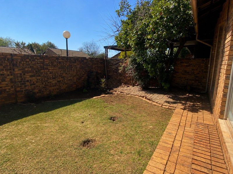 A private rear garden featuring a brick-paved patio area, established lawn, and perimeter brick boundary walls.