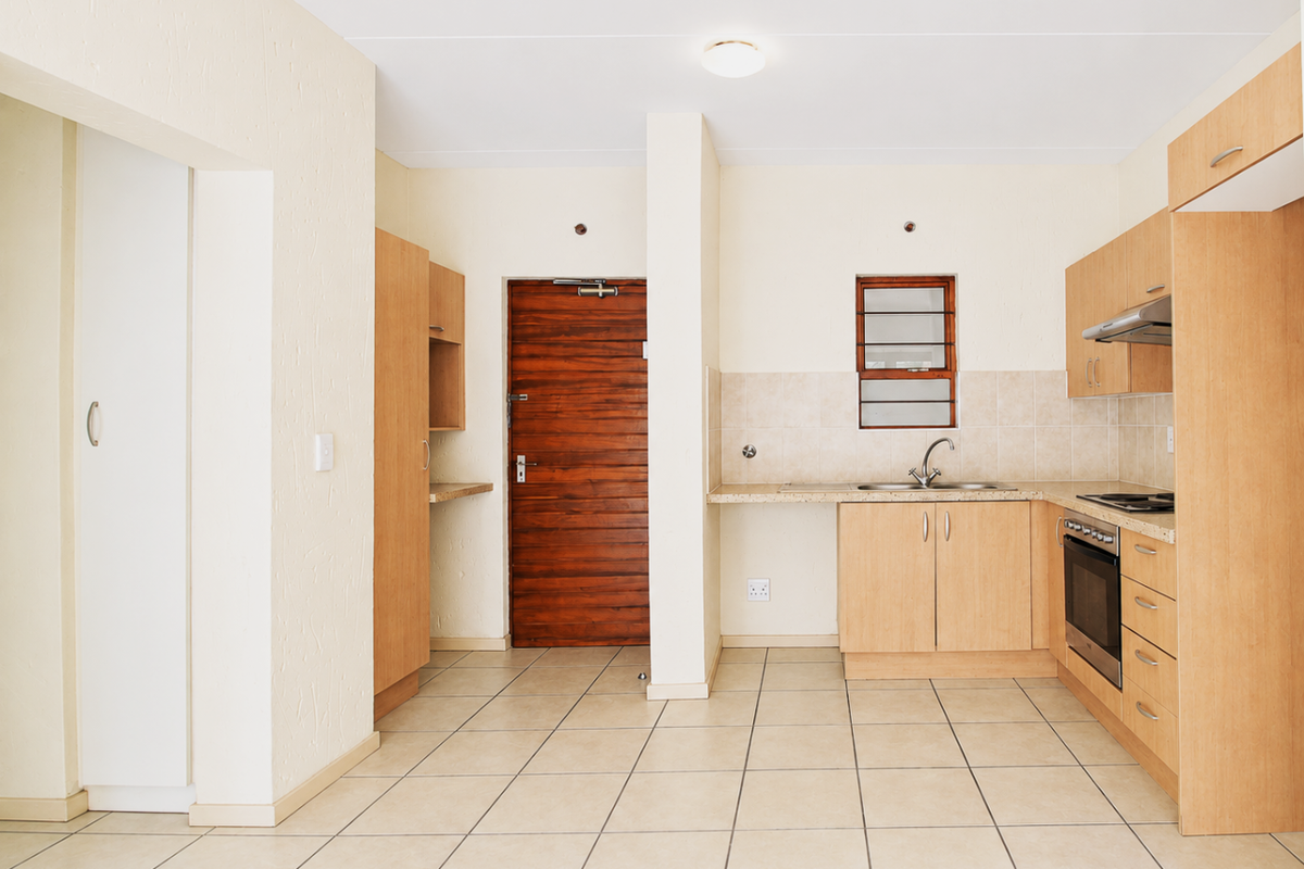 A functional, empty kitchen featuring light wood cabinetry, tiled flooring, a built-in oven, and a tiled backsplash, offering a clean canvas for updates.