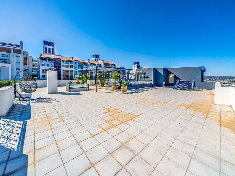 Spacious rooftop terrace featuring a pergola, built-in seating, and solar water heating panels, offering an expansive outdoor entertainment area.