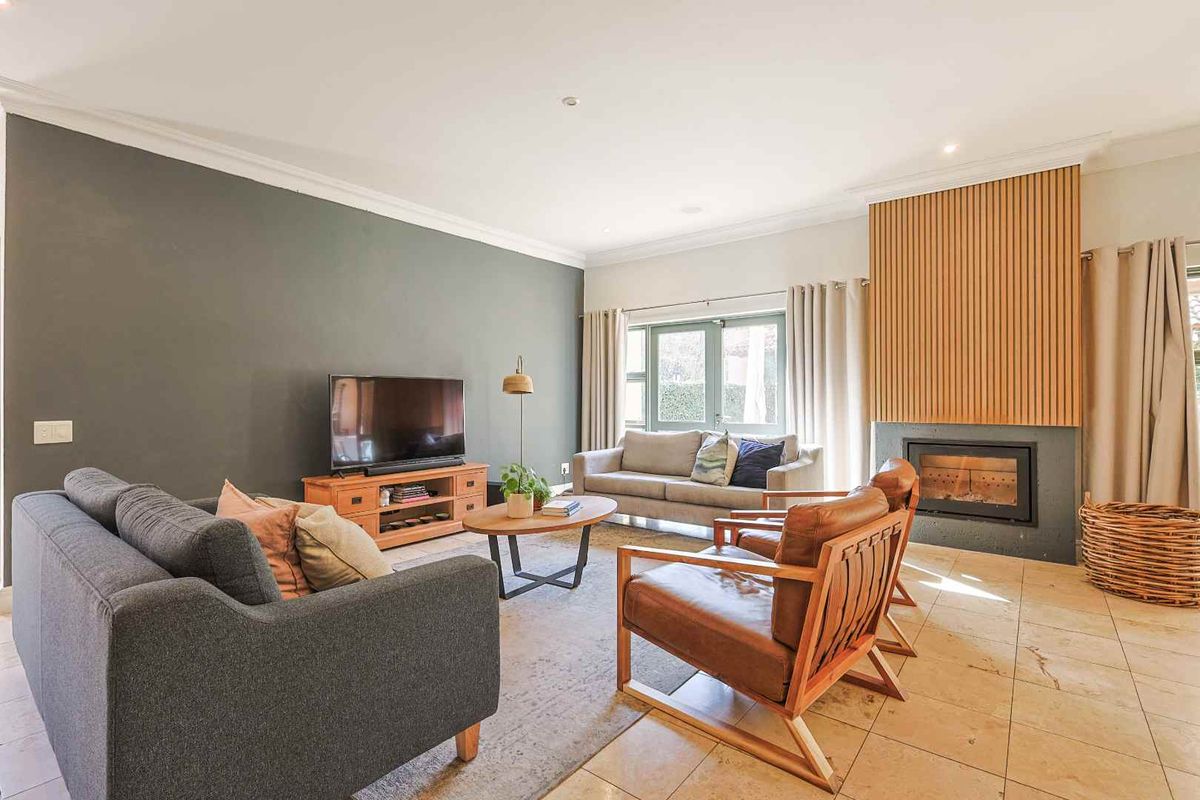 A well-maintained living room featuring a modern fireplace with a timber slat feature wall, tiled flooring, and neutral decor.