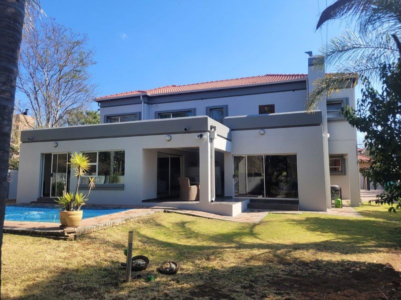 Rear view of a two-story house featuring a swimming pool, covered patio area, and sliding glass doors leading to the interior.