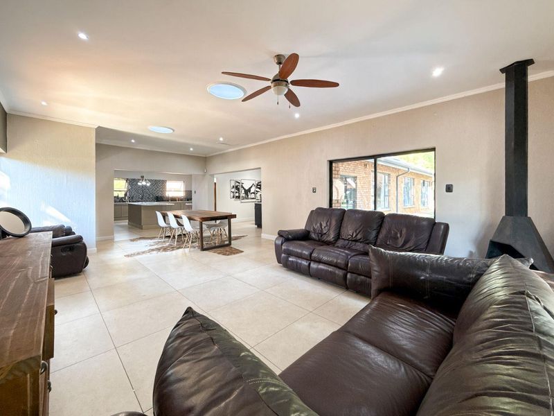 Spacious open-plan living and dining area featuring tiled floors, a modern fireplace, skylights, and a seamless flow into the well-appointed kitchen.