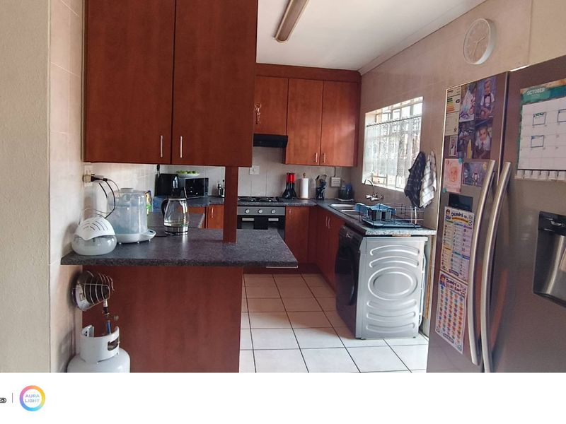 A functional kitchen featuring wooden cabinetry, laminate countertops, built-in oven and hob, and tiled flooring, providing a practical workspace for daily cooking.