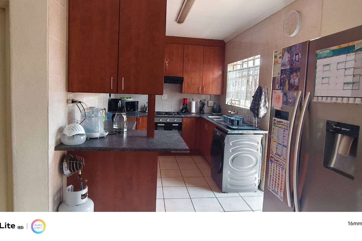 A functional kitchen featuring wooden cabinetry, laminate countertops, built-in oven and hob, and tiled flooring, providing a practical workspace for daily cooking.