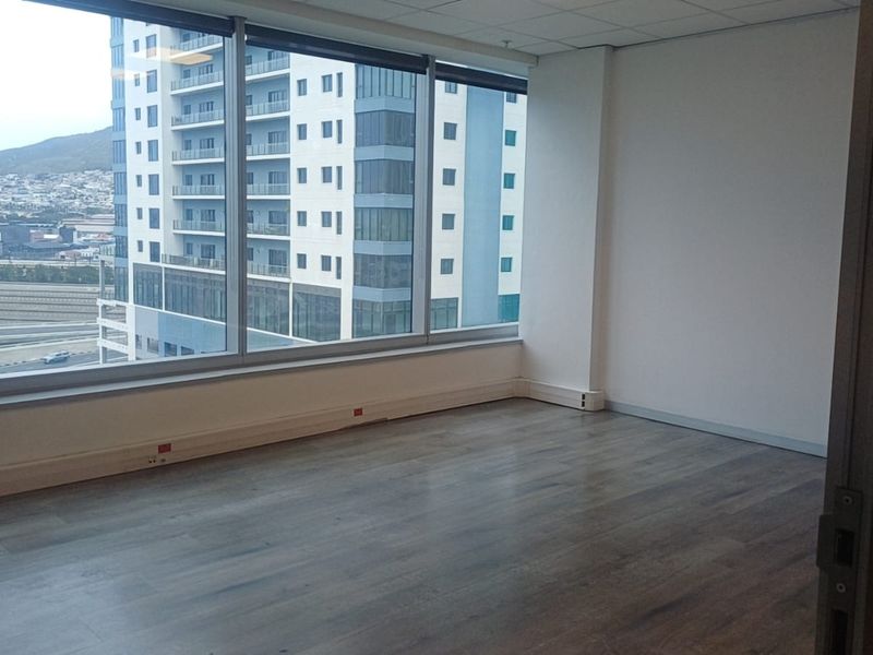 A bright, empty office space featuring floor-to-ceiling windows with city views, laminate flooring, and a clean, modern finish.