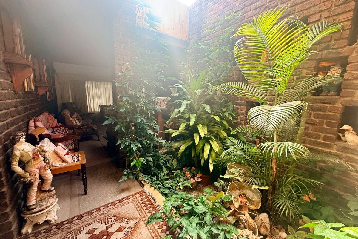 An indoor atrium or courtyard area featuring exposed brick walls, a skylight, and integrated garden space adjacent to the living area.