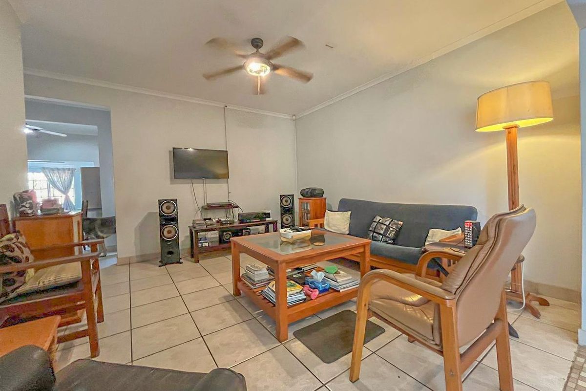 A comfortable living room featuring tiled flooring and a ceiling fan, providing a functional and open space for relaxation.