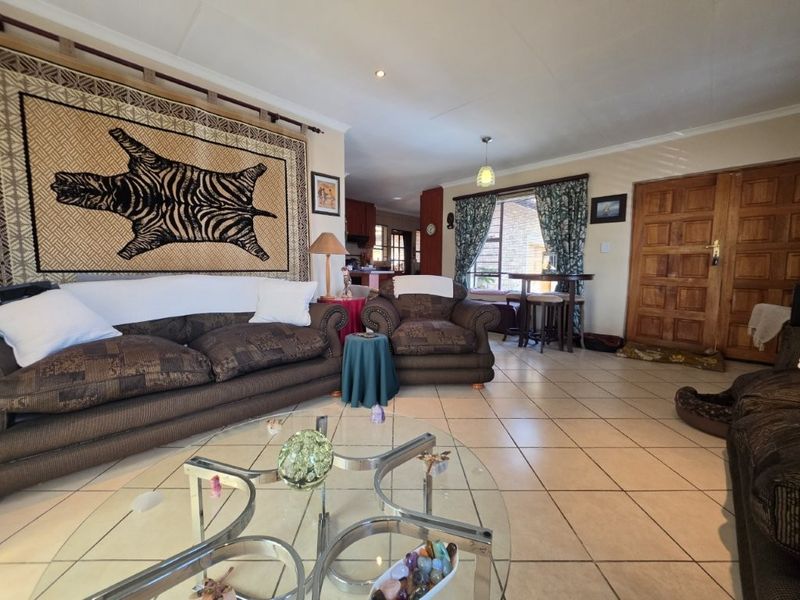 Open plan living area featuring tiled flooring, recessed lighting, and a solid timber entrance door, providing a functional and connected space.