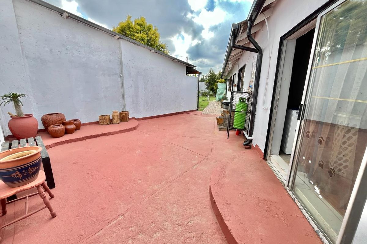 A rear exterior patio area featuring a painted concrete surface, sliding door access, and boundary walling, providing a functional outdoor space.