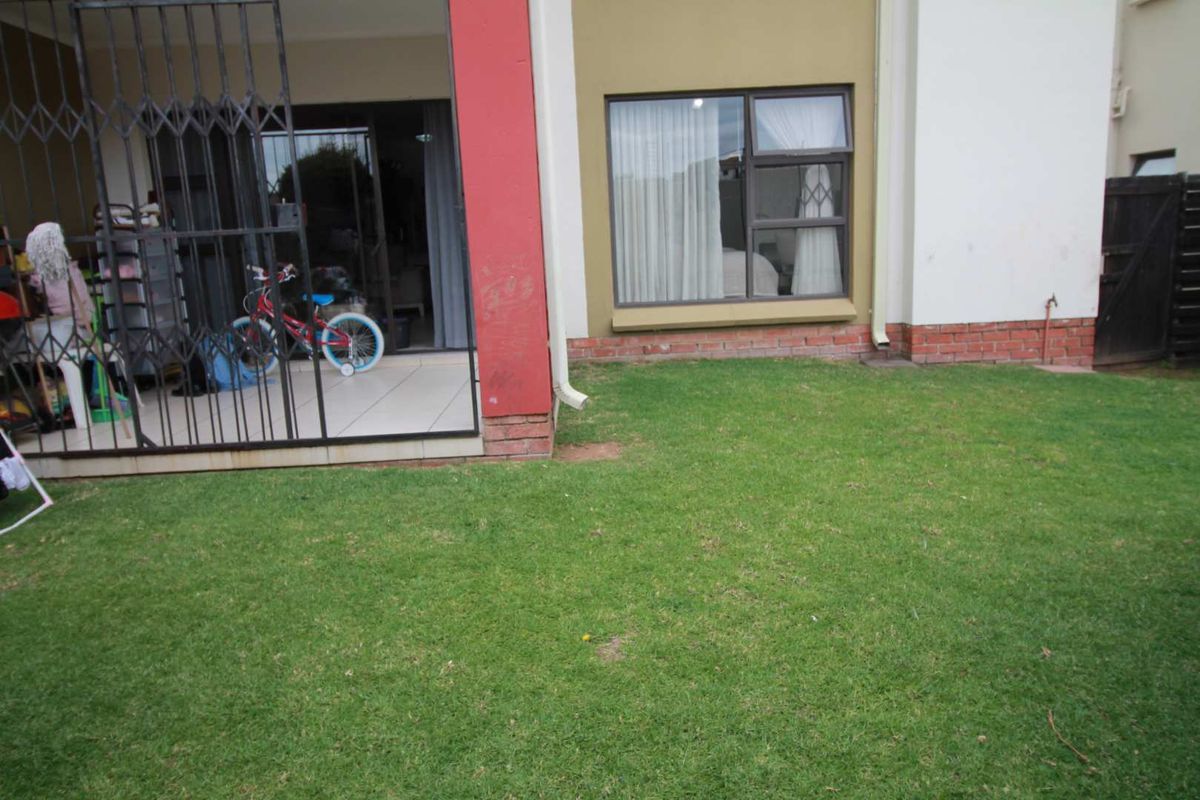 A view of the rear garden area featuring a paved patio with security gate and access to the interior living space.