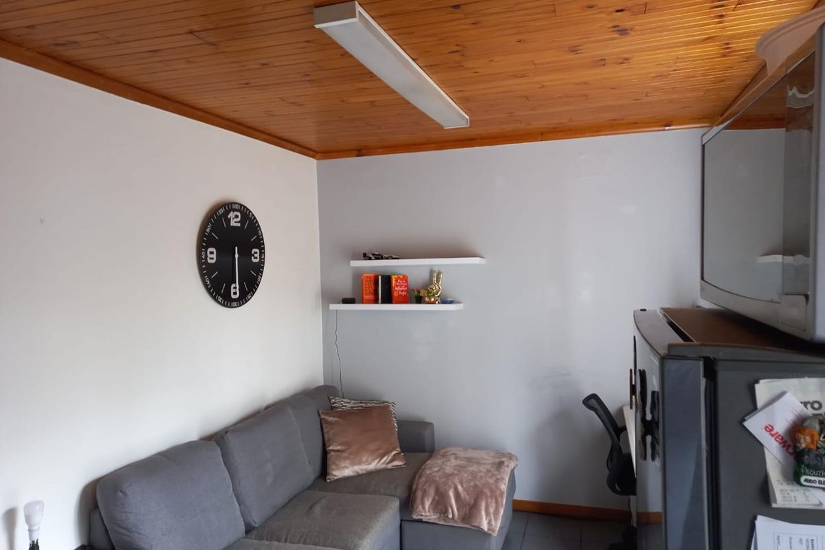 A living area featuring a timber tongue and groove ceiling, tiled flooring, and wall-mounted floating shelves.
