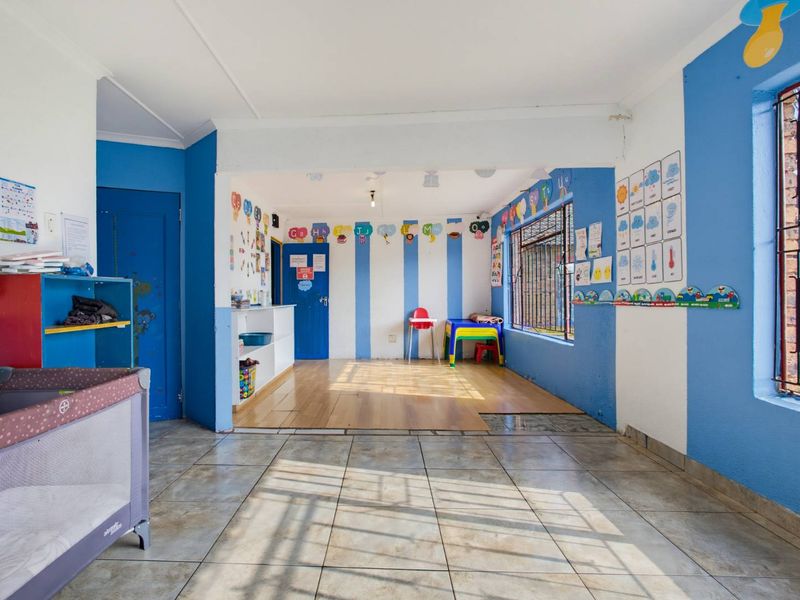 A multi-purpose living area featuring a mix of tiled and laminate flooring, security bars on windows, and built-in storage shelving.