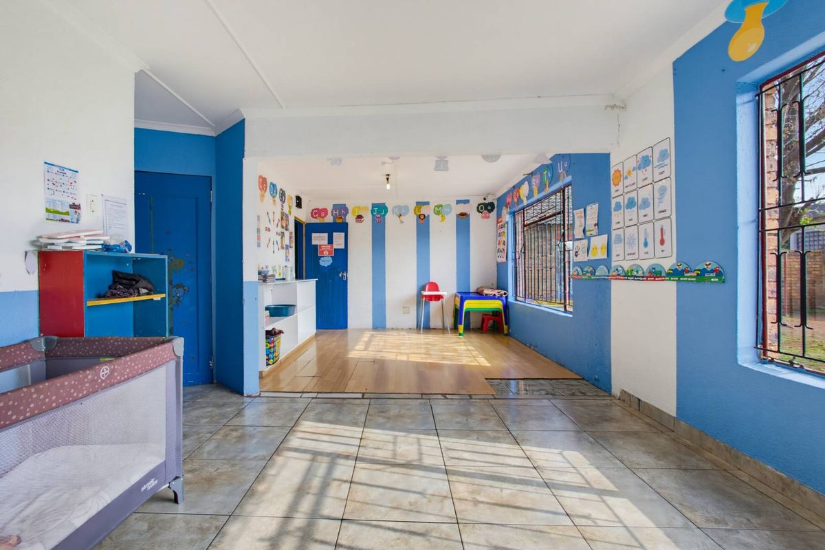 A multi-purpose living area featuring a mix of tiled and laminate flooring, security bars on windows, and built-in storage shelving.