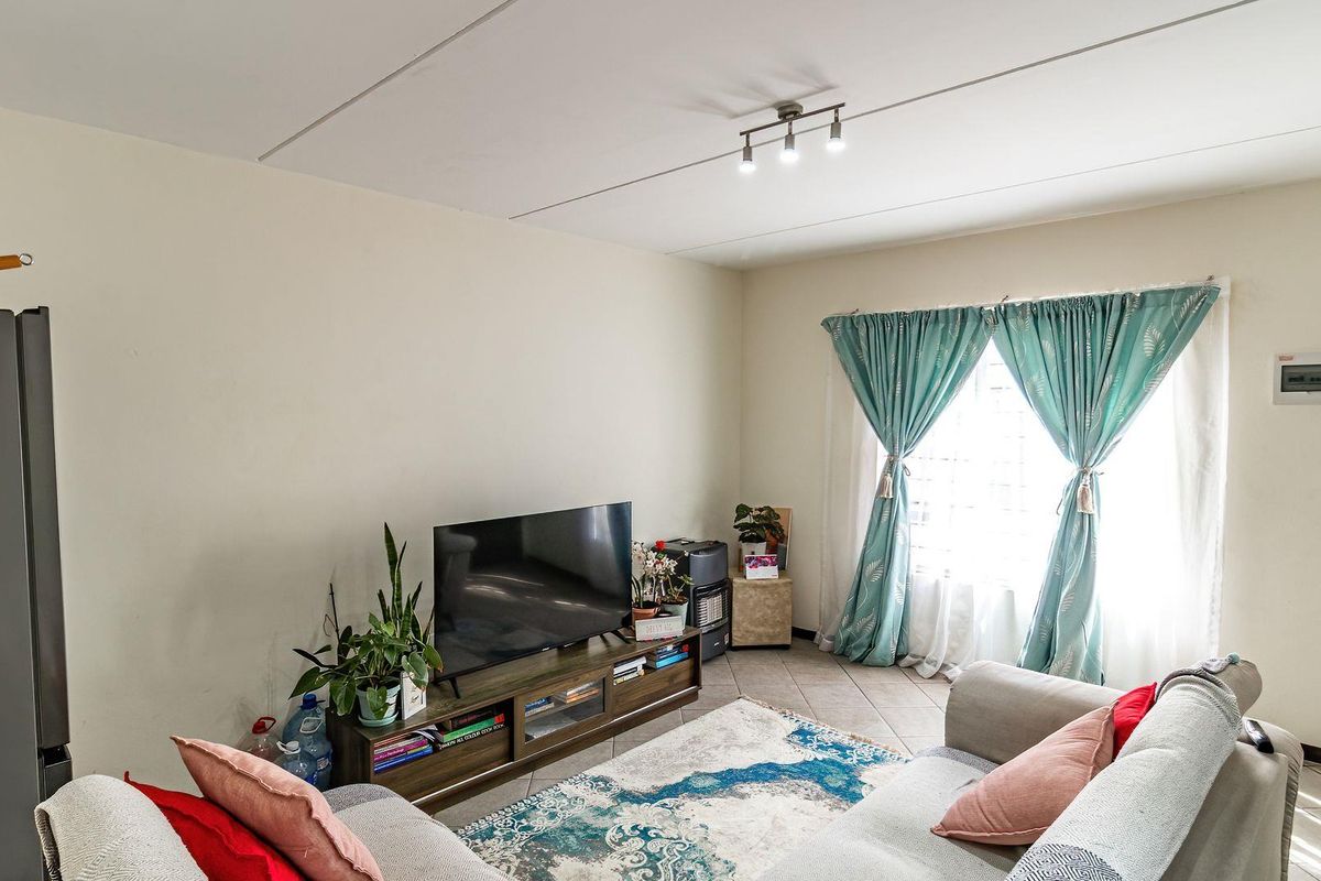 A living room featuring tiled flooring and a ceiling-mounted spotlight fixture, providing a functional and well-lit space.