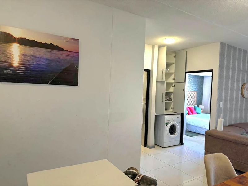 A functional laundry area featuring built-in cabinetry and tiled flooring, conveniently located within the apartment layout.