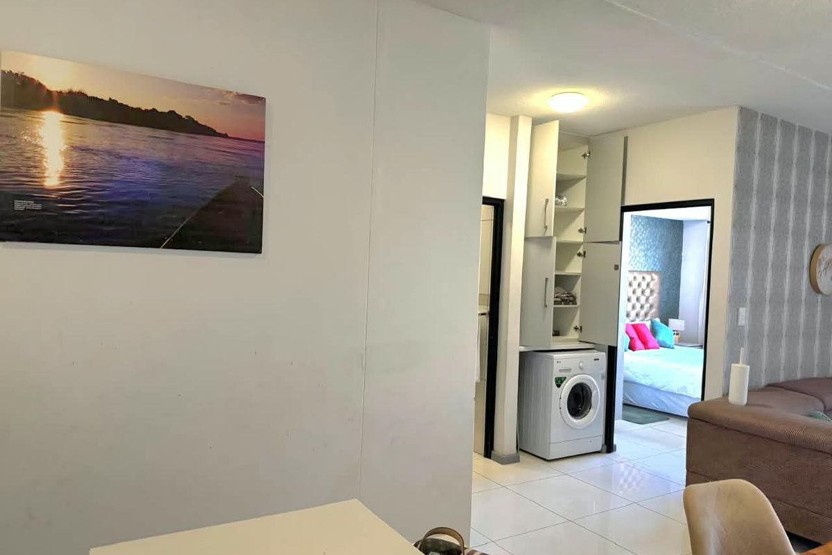 A functional laundry area featuring built-in cabinetry and tiled flooring, conveniently located within the apartment layout.