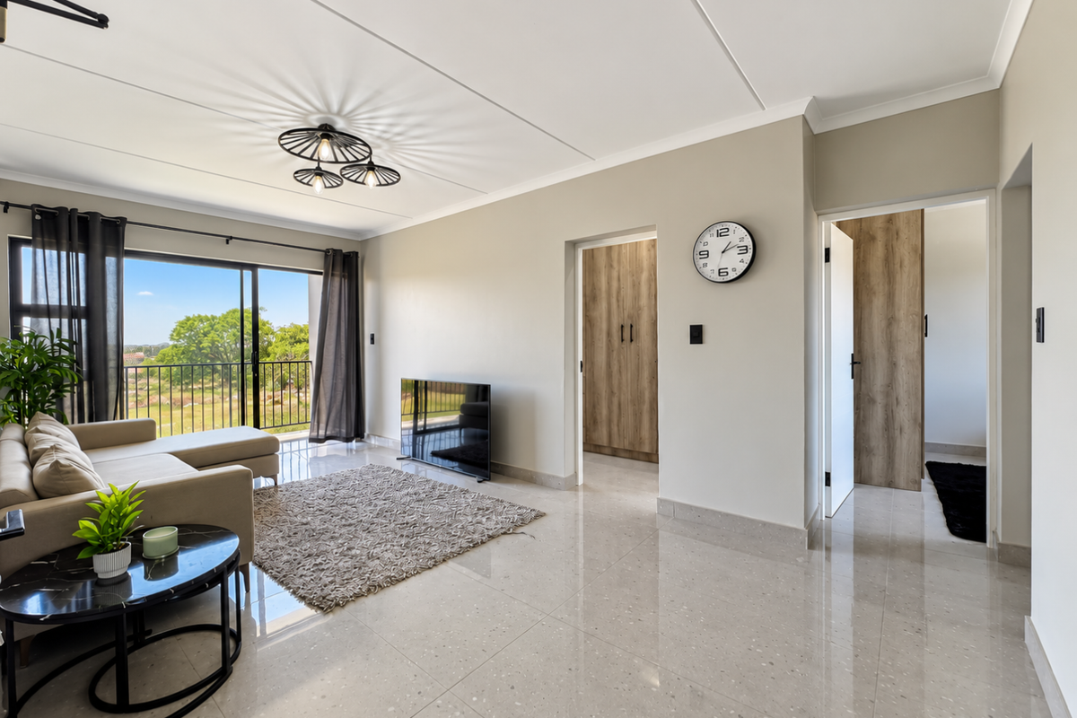 Bright and modern living room featuring large sliding glass doors leading to a balcony, polished tiled floors, and neutral wall finishes.