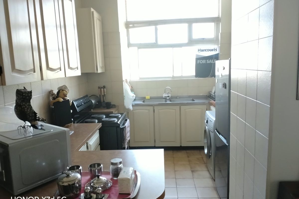 A functional kitchen featuring built-in cabinetry, a double basin sink, tiled splashbacks, and dedicated plumbing for a washing machine.