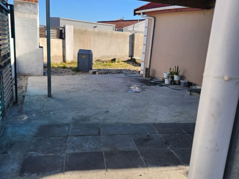 A covered outdoor patio area featuring a mix of concrete and tiled flooring, providing a functional space for outdoor living and entertainment.