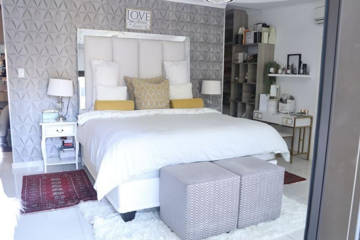 A well-maintained bedroom featuring a textured feature wall, tiled flooring, and built-in shelving units.
